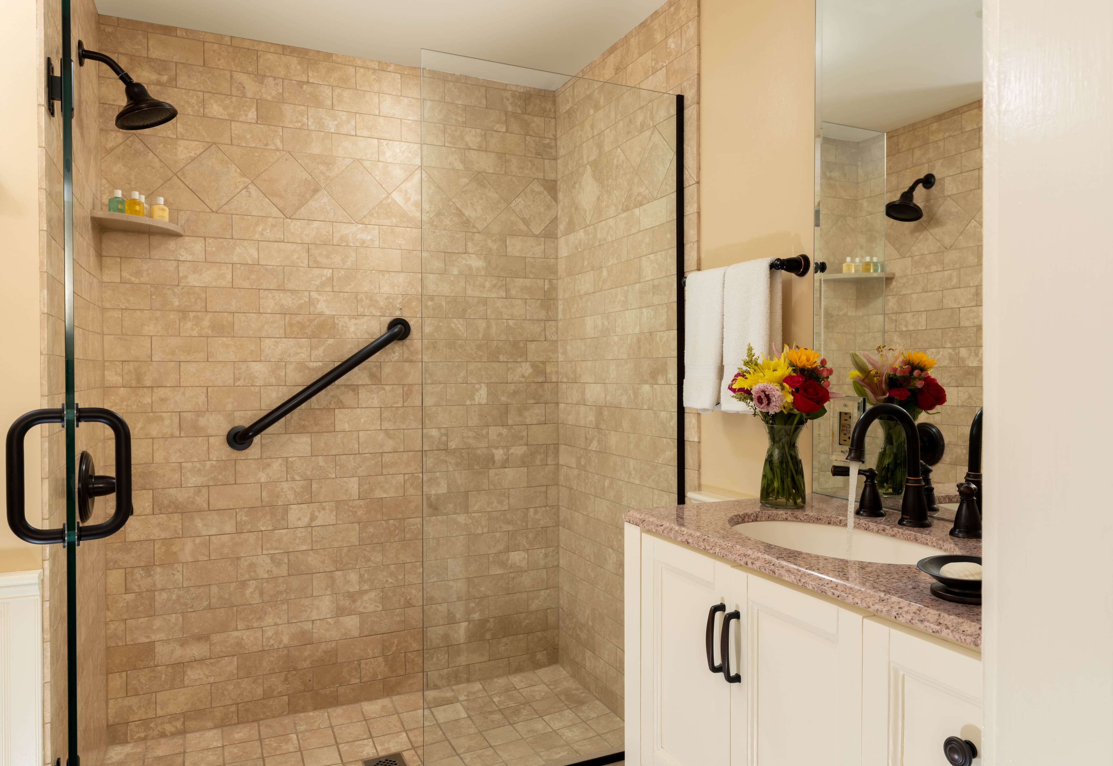 Glass enclosed step in shower with clear glass and brown stone