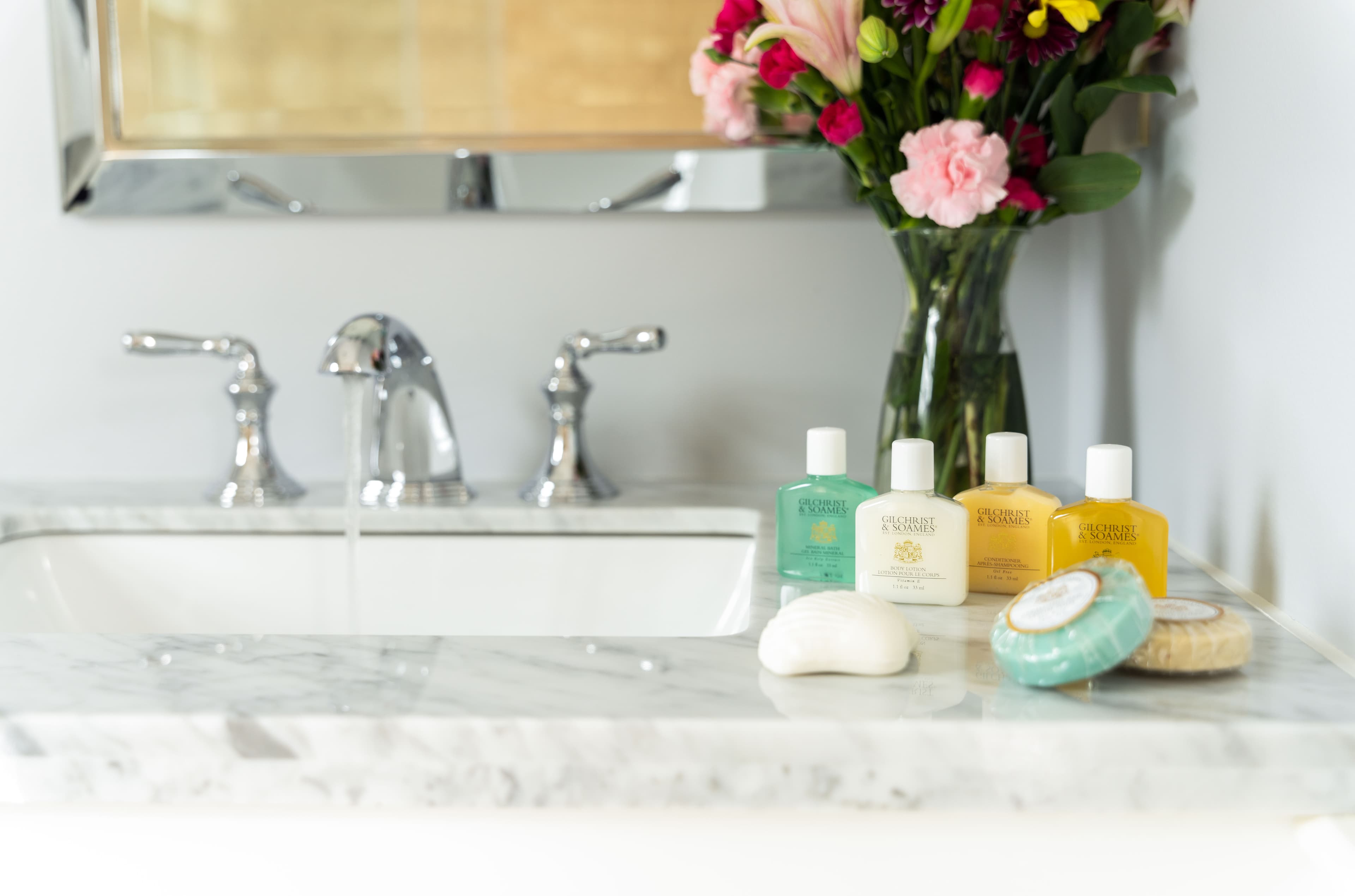 Bathroom vanity with marble top and bouquet of flowers & amenities on display