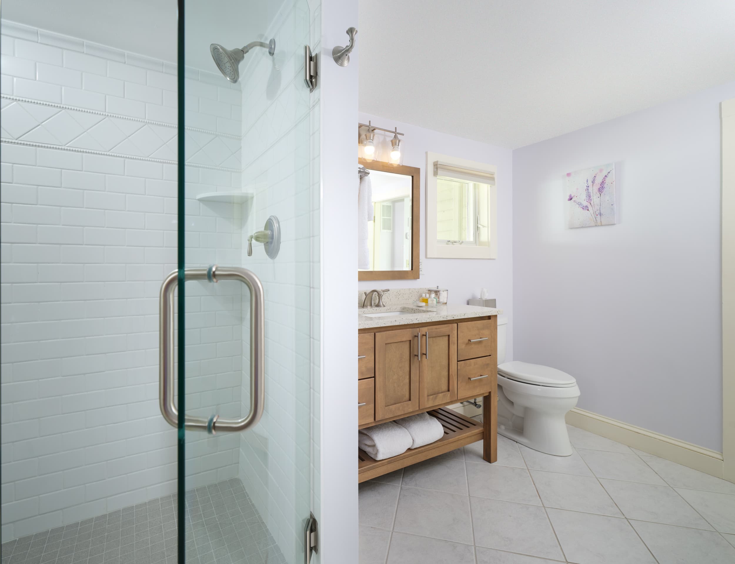 Luxury bathroom with glass enclosed shower and wooden vanity by the toilet