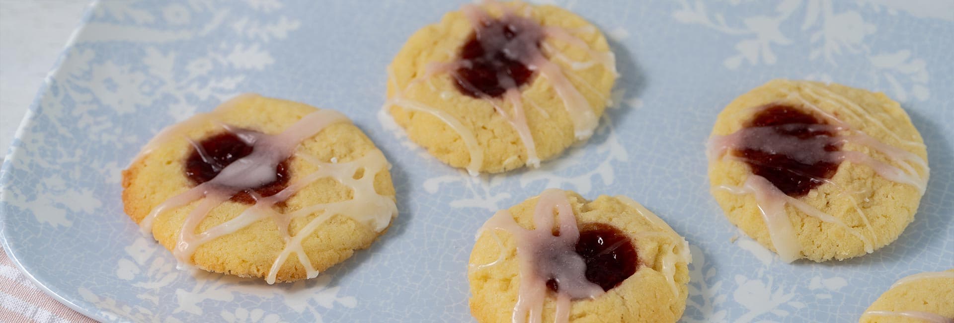 A plate of jam-filled cookies drizzled with icing.