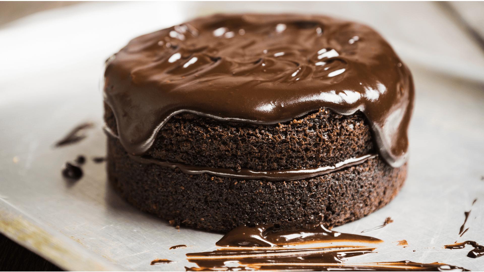 A round chocolate cake topped with glossy chocolate ganache.