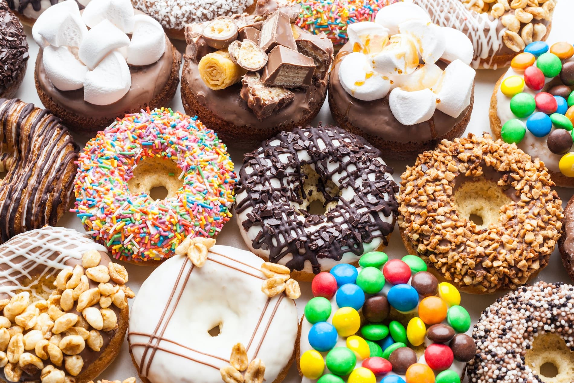 A colorful assortment of decorative donuts topped with sprinkles, chocolate, marshmallows, and various candies.