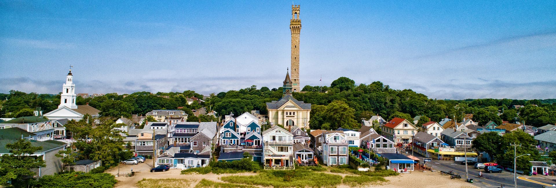 A coastal town with colorful houses and a tall monument in the background.