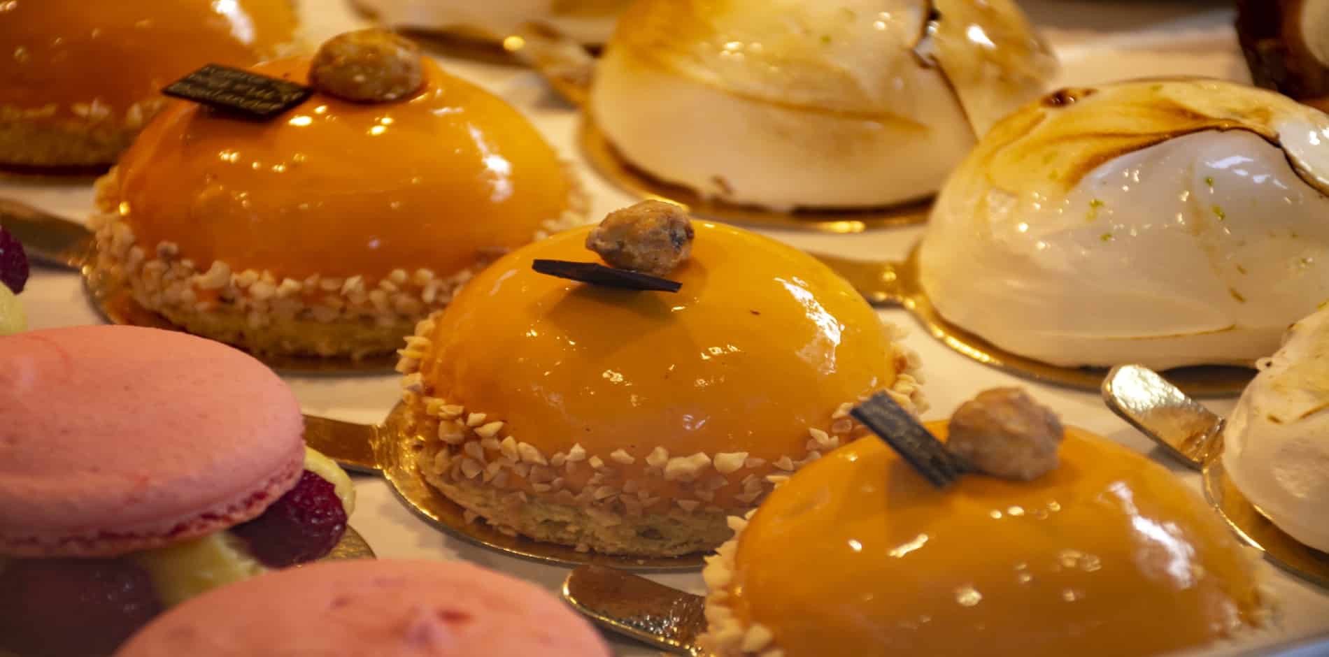 An assortment of colorful pastries, including bright orange dome-shaped desserts and pink macarons.
