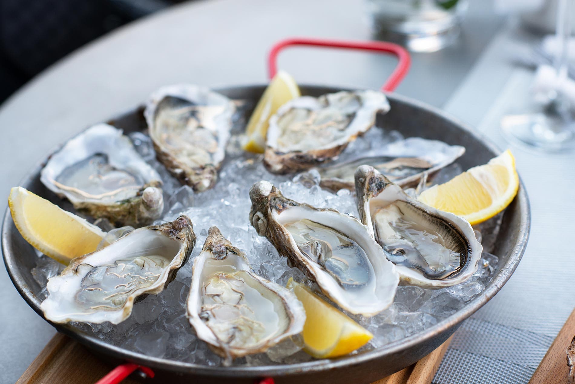 A platter of fresh oysters on ice, garnished with lemon wedges.