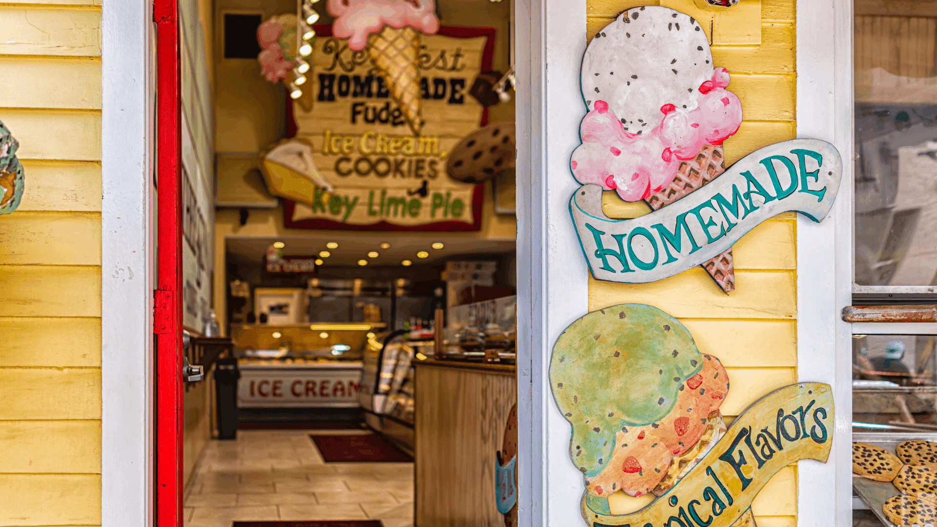A colorful ice cream shop entrance with signs advertising homemade treats and tropical flavors.