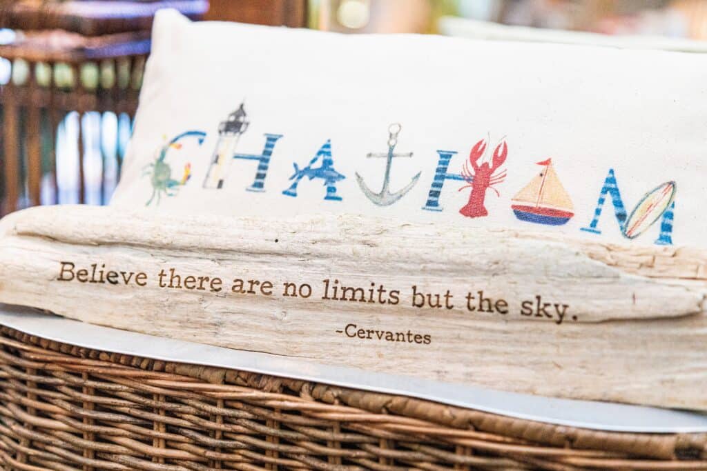 A decorative pillow featuring colorful letters spelling "CHAITOM" above a quote by Cervantes: "Believe there are no limits but the sky."