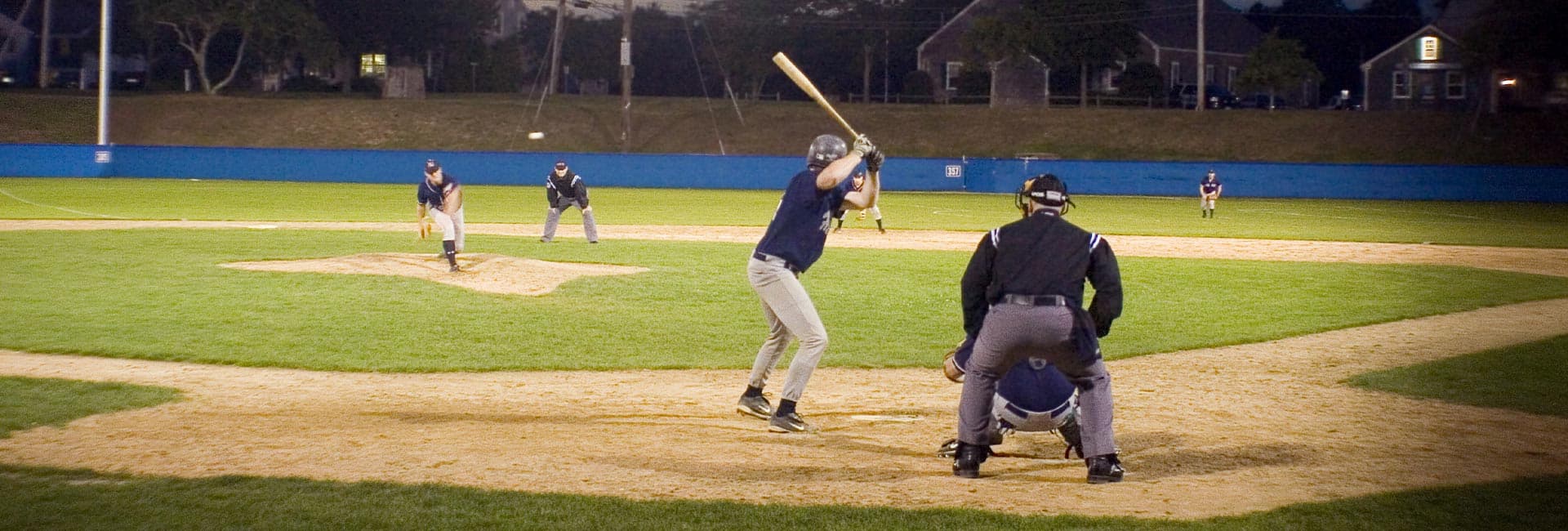 A baseball player is poised to hit while a pitcher throws from the mound and an umpire watches closely.