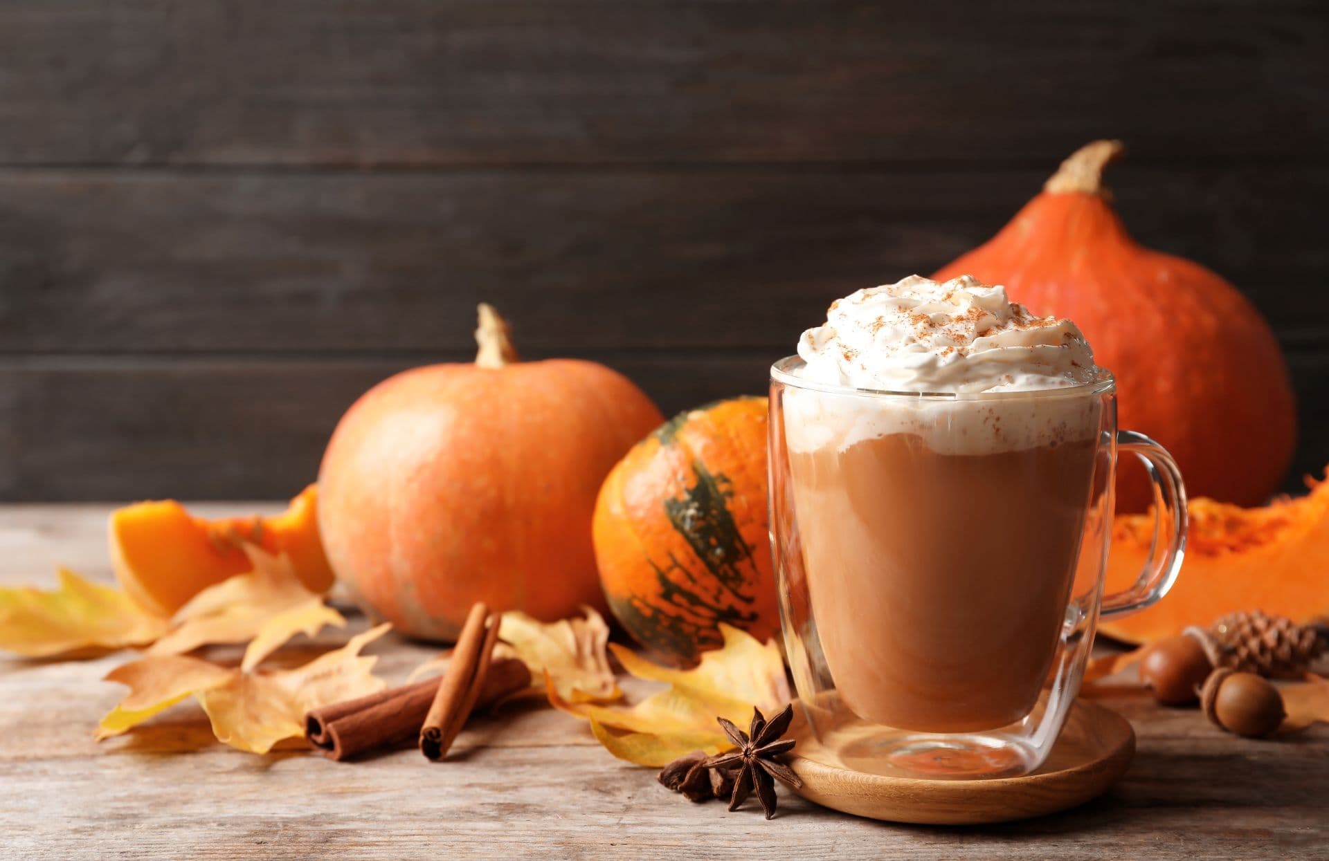 A Pumpkin Spice Latte on a table with fresh pumpkins A Pumpkin Spice Latte on a table with fresh pumpkins