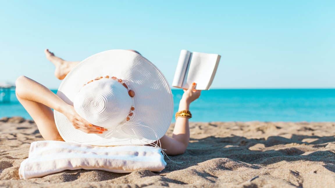 Portrait of a young women relaxing on the beach, reading a book