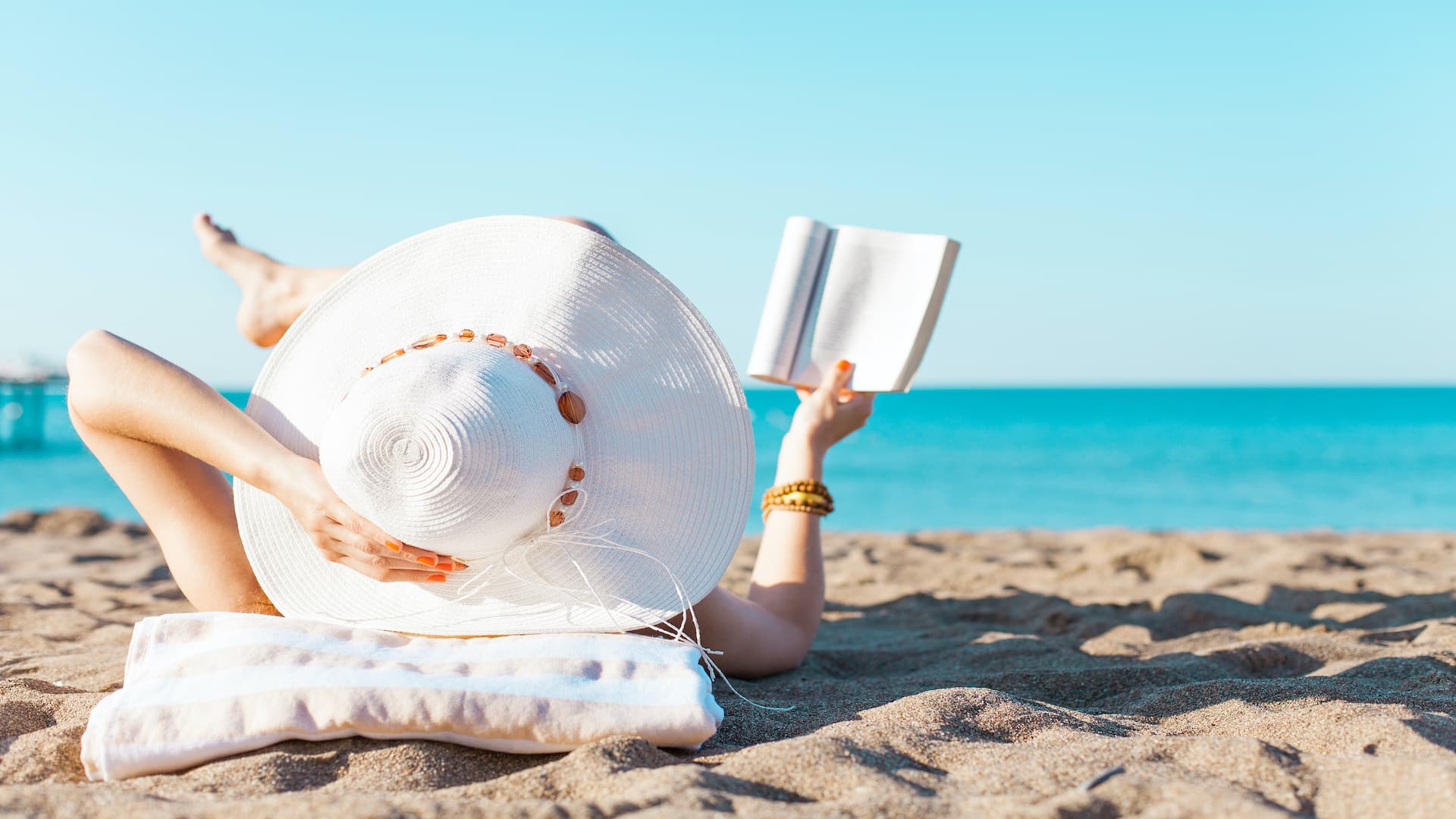 Portrait of a young women relaxing on the beach, reading a book