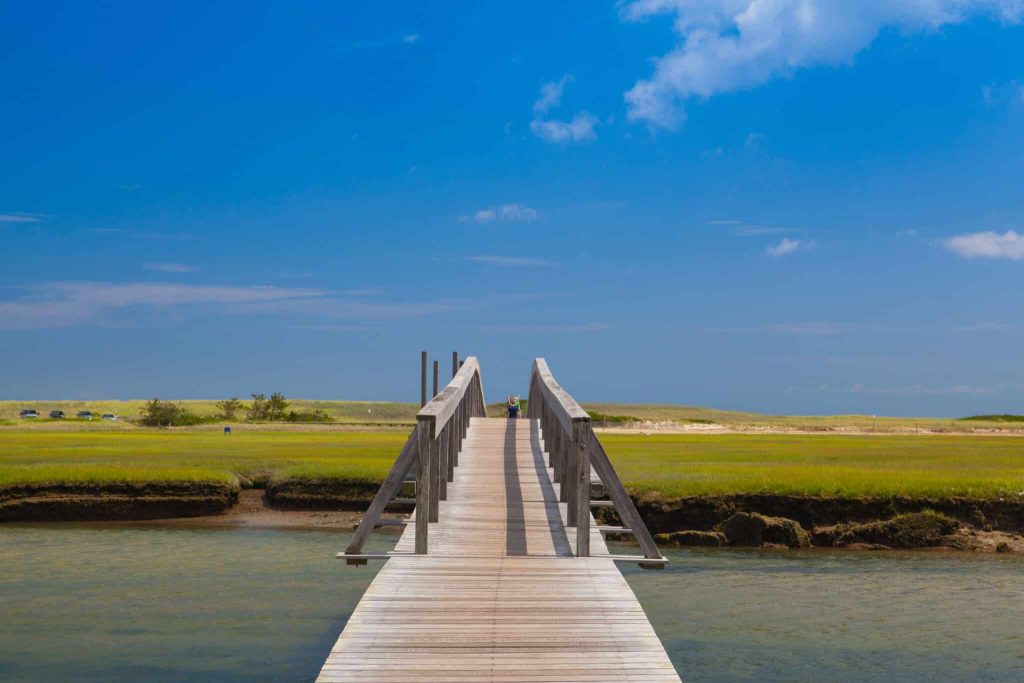 Walkway to the dunes wooden walkway extends over marshland toward the distant dunes and ocean In Sandwich, Cape Cod, Massachusetts,