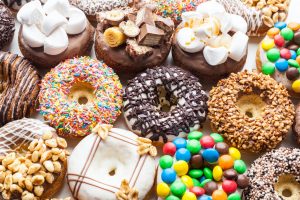 Close up of a selection of colorful donuts decorated with chocolate, candies, nuts, sprinkles