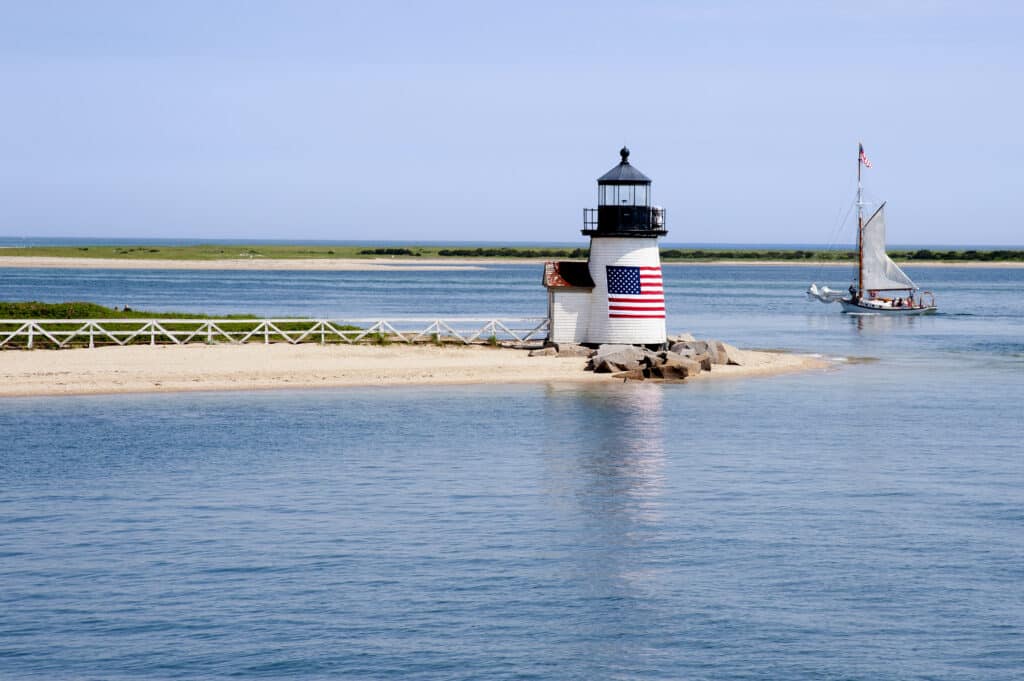 Sailing past Brant Point lighthouse on Nantucket Island on a warm quet summer day in New England.