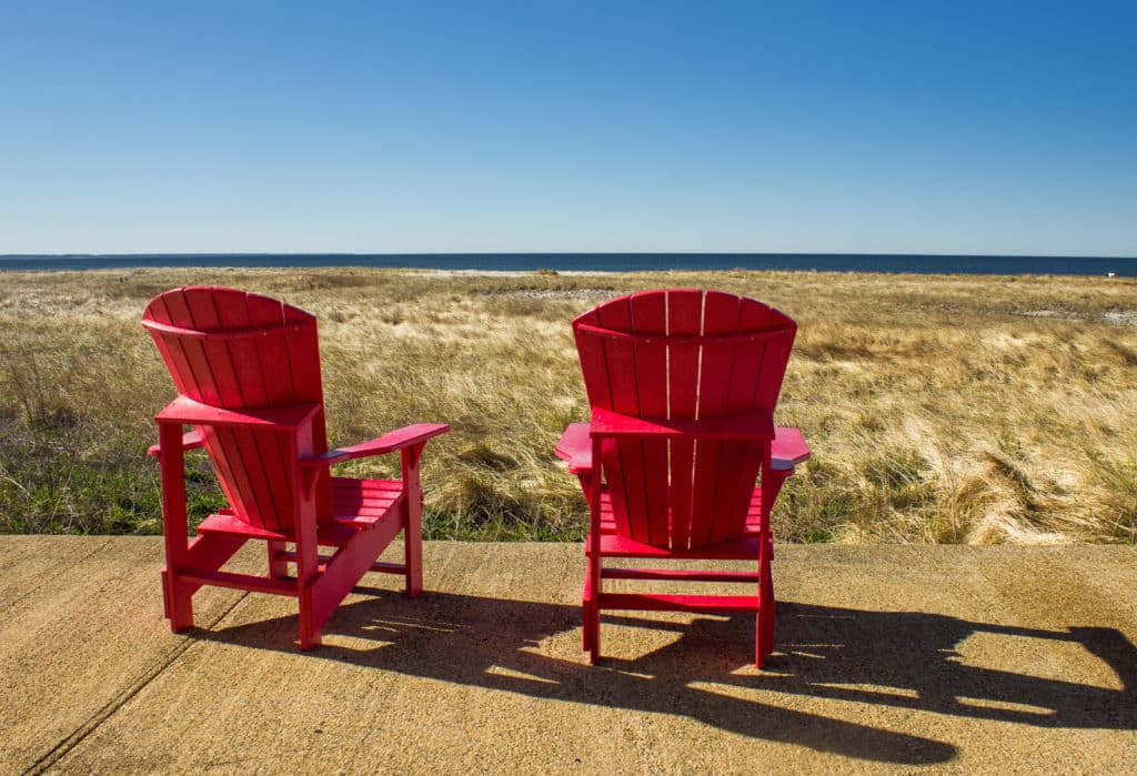 Red Adirondack beach chair on a deck on sandy beach near Provincetown (Cape Cod), Concept of perfect calm day on the sea