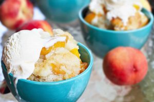 Peach Cobbler in a aqua color bowl topped with vanilla ice cream