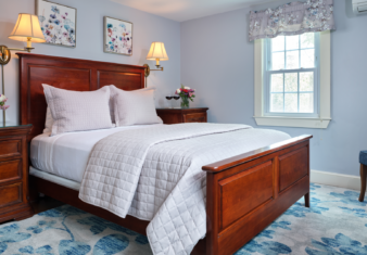 A guest room with a wooden Queen Size bed and two bedside tables