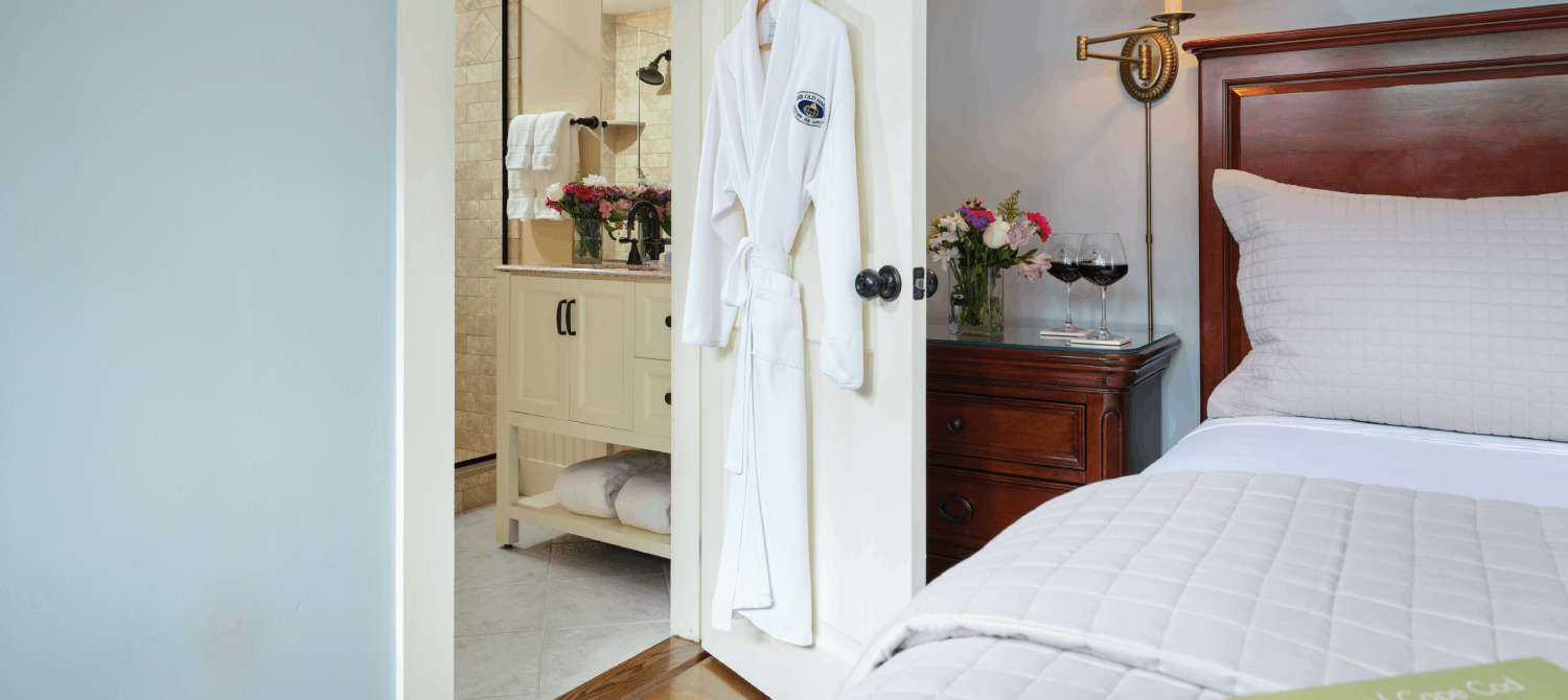 Bedroom with king bed and doorway with white hanging robe open to bathroom