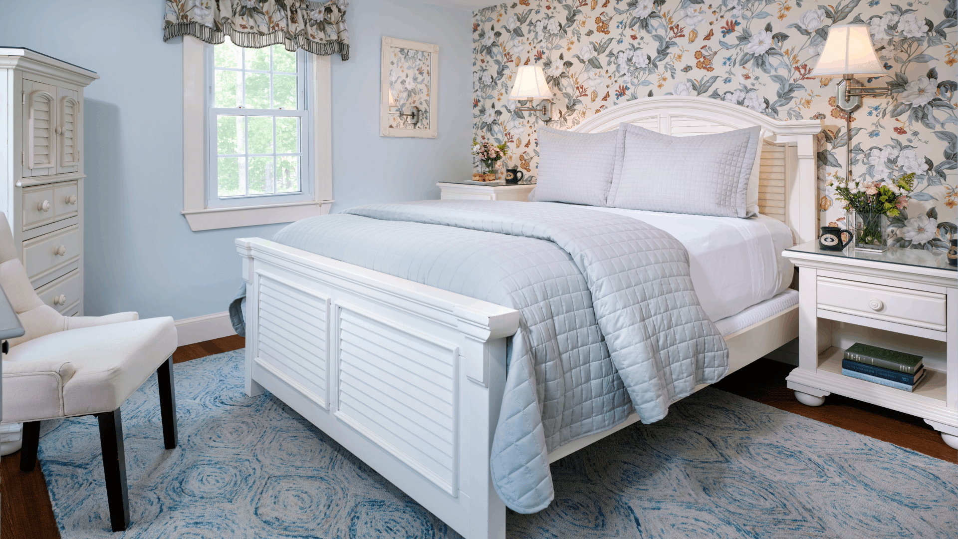 Elegant bedroom with floral wallpaper, queen bed, sitting chairs and window