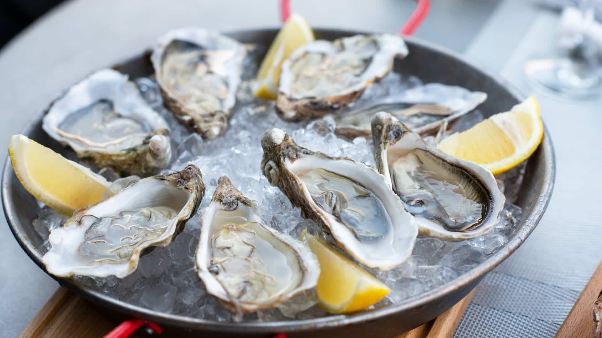 Oysters on a plate over ice decorated with lemon wedges