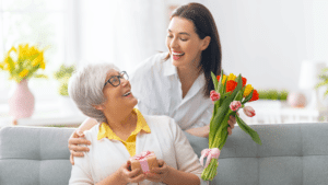 Mother holding gift and Daughter holding flowers looking at each other 