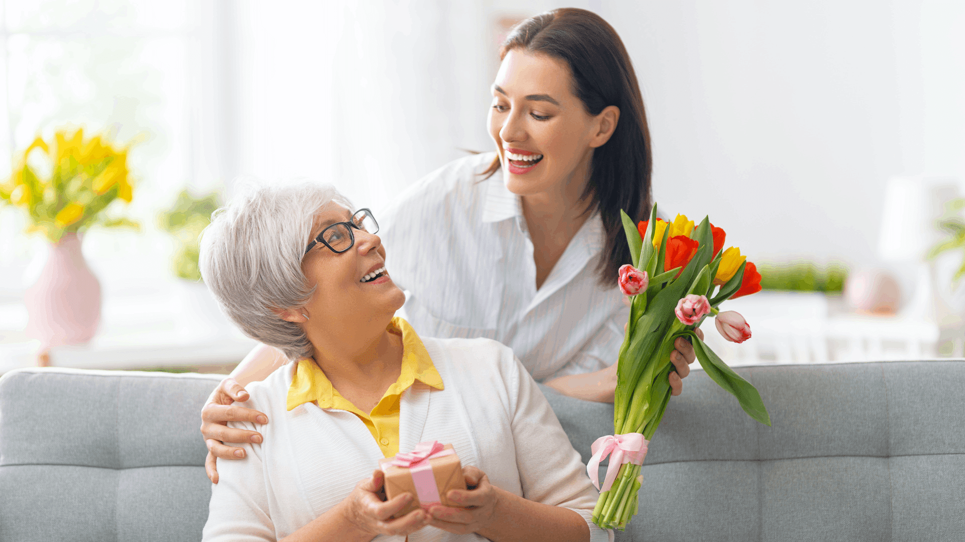 Mother holding gift and Daughter holding flowers looking at each other