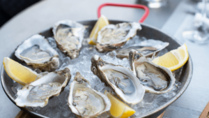 Raw Oysters and lemon wedges in a dish with ice 