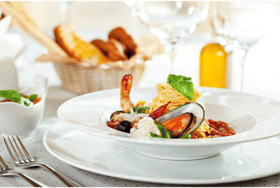 A white plait served with seafood pasta dish and bread basket on back ground