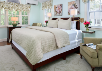 Bedroom with king bed decorated in green, one green reading chair and green rug