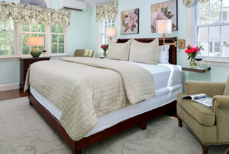 Bedroom with king bed decorated in green, one green reading chair and green rug