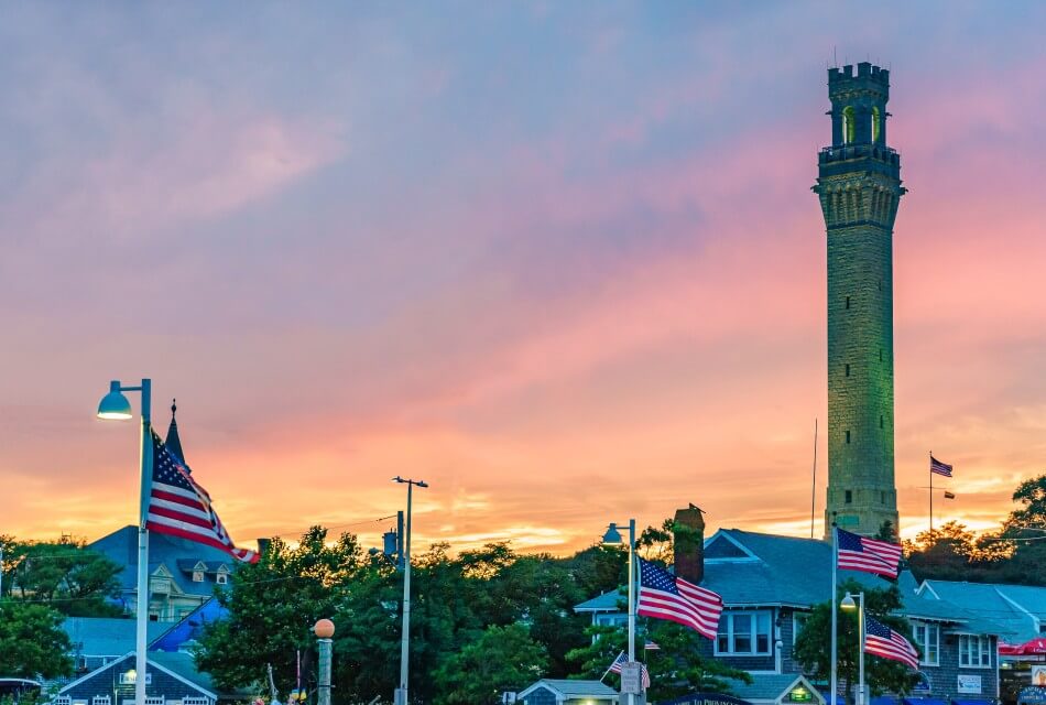 A towering monument by numerous American flags against a sunset sky