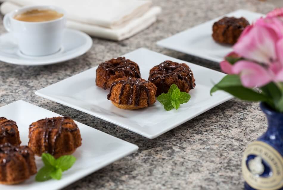 Three white plates each with three homemade baked goods and a mint leaf