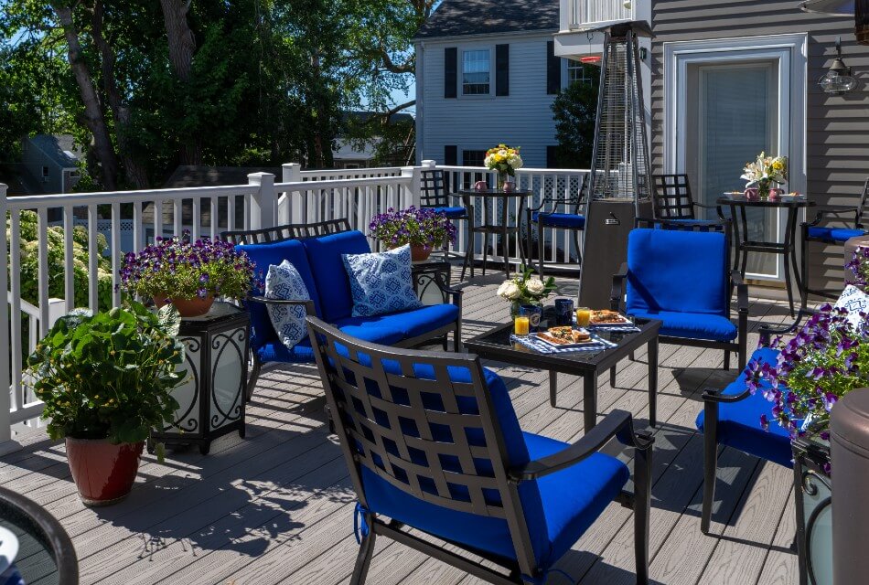 Large outdoor deck with patio chairs and tables and many potted flower plants