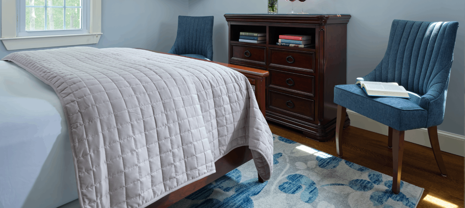 Interior photo of a bedroom with queen bed, two reading chairs and a bureau decorated in blue colors