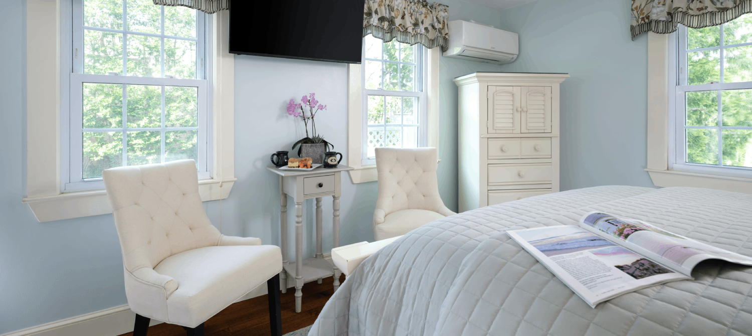 Bedroom with two sitting chairs, dresser and queen bed