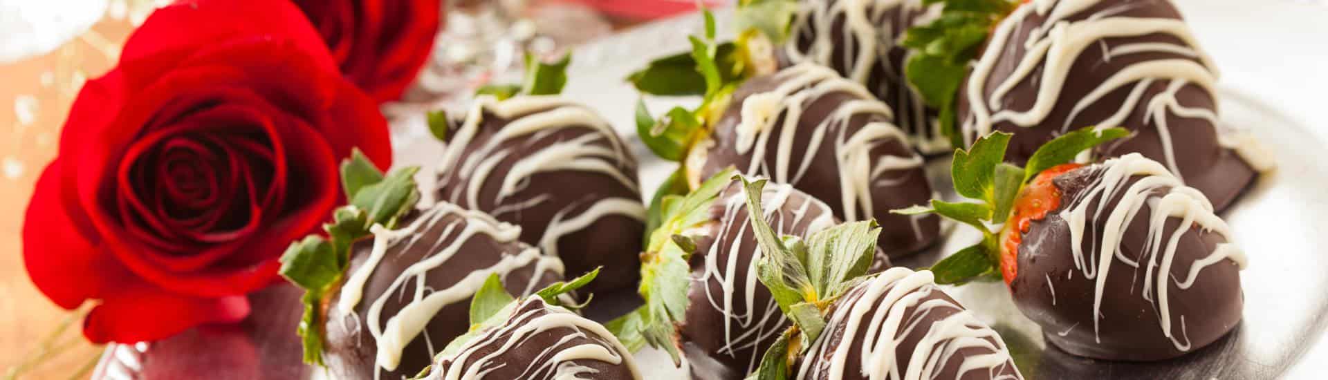 A silver platter with chocolate covered strawberries and a red rose