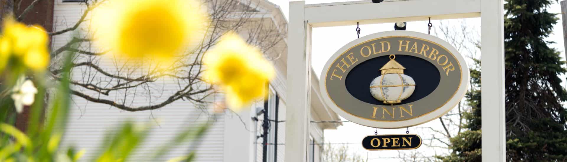 Grey, gold and navy oval business sign on white posts by yellow flowers