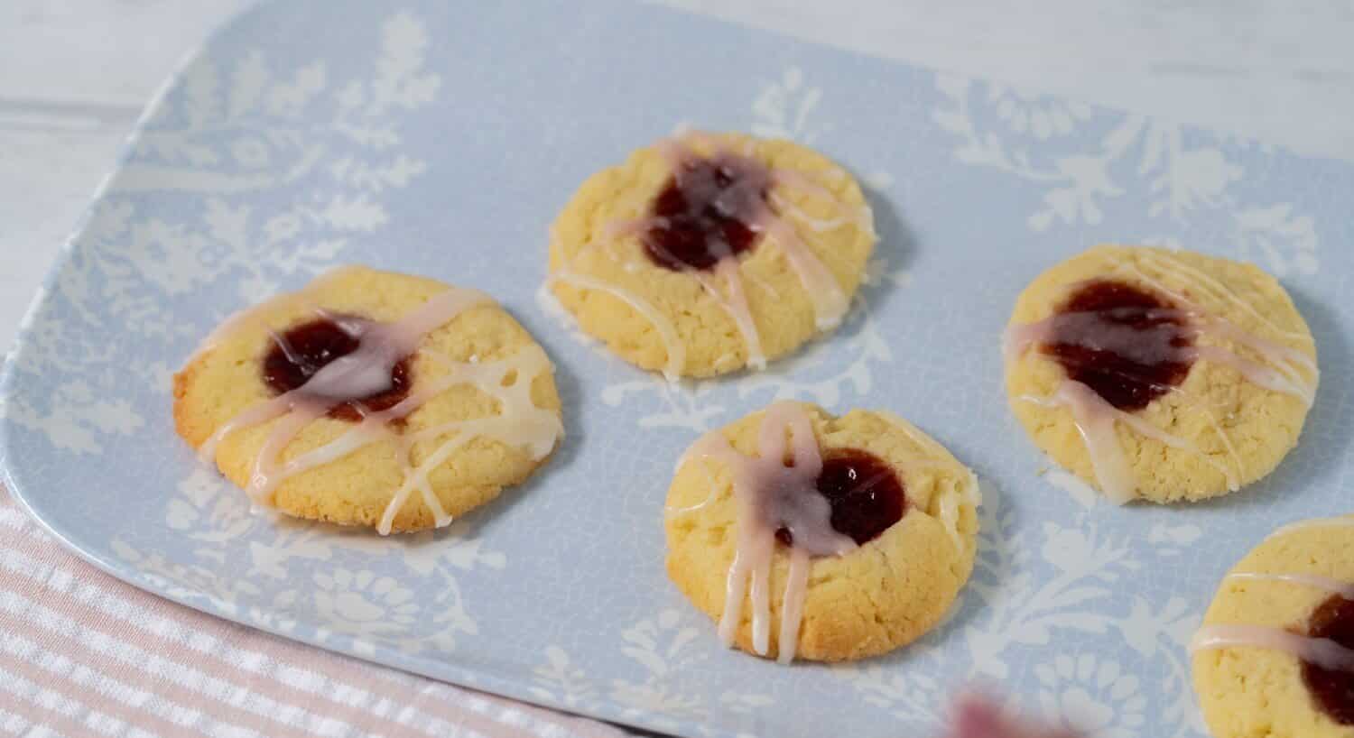 Five homemade thumbprint cookies on a blue and white floral plate
