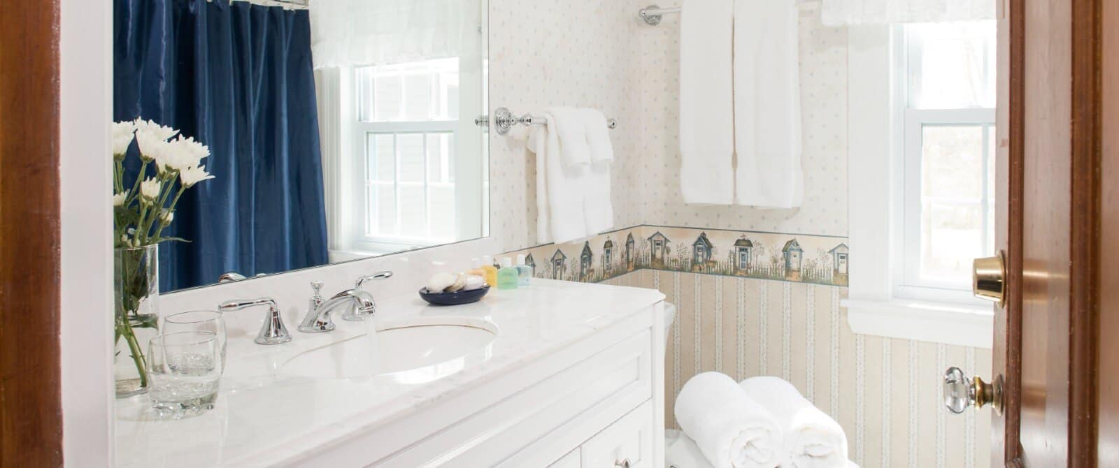 Bathroom with pale blue walls, vanity with framed mirror and white hanging towels