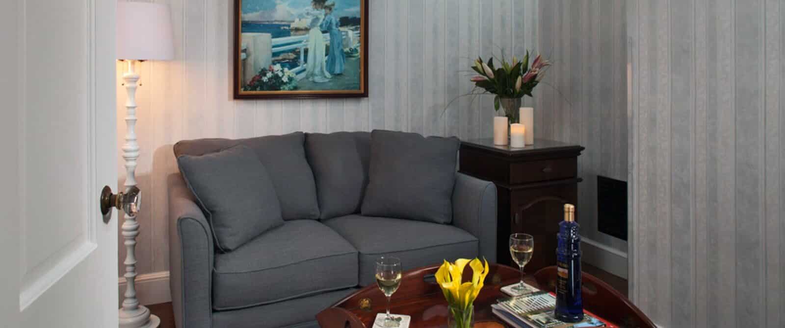 Corner of a bedroom with loveseat, coffee table and side table with candles and vase of flowers
