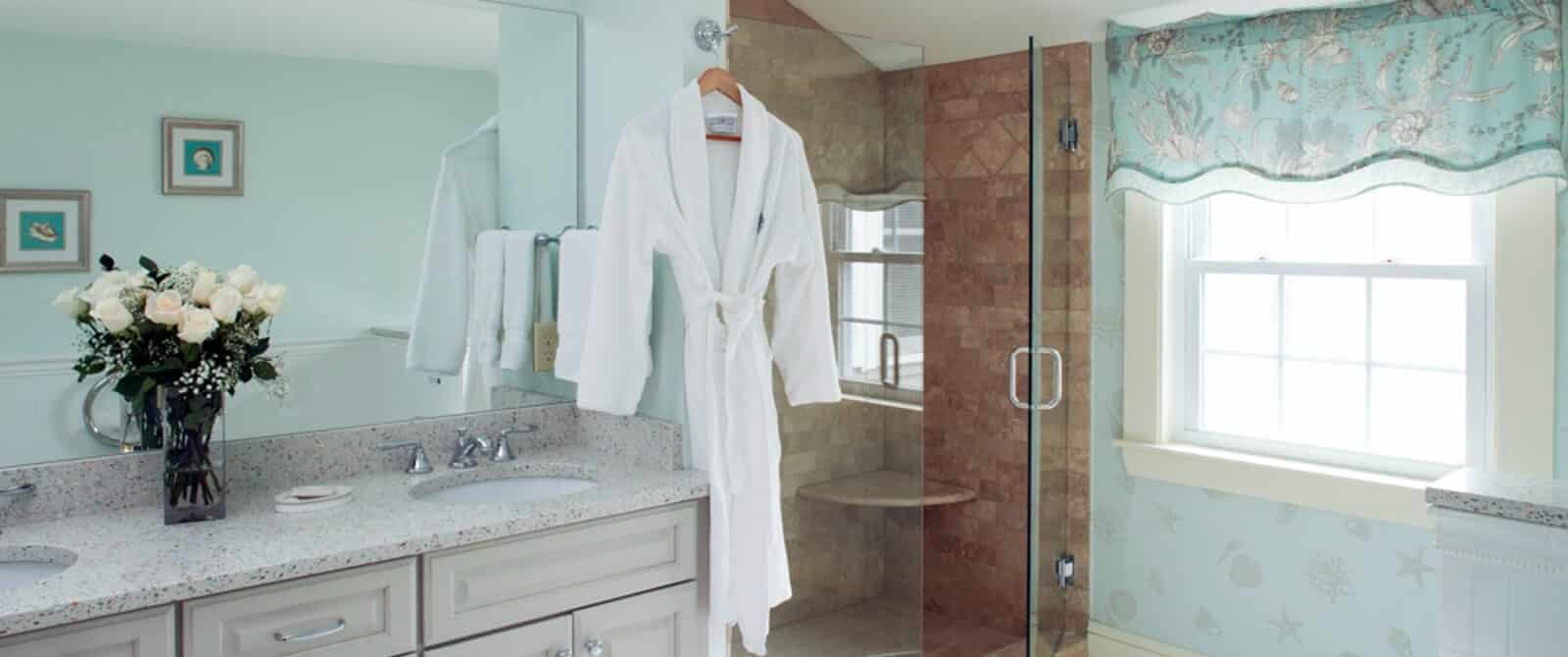 Bright bathroom featuring shower with glass doors, two sink vanity and large window