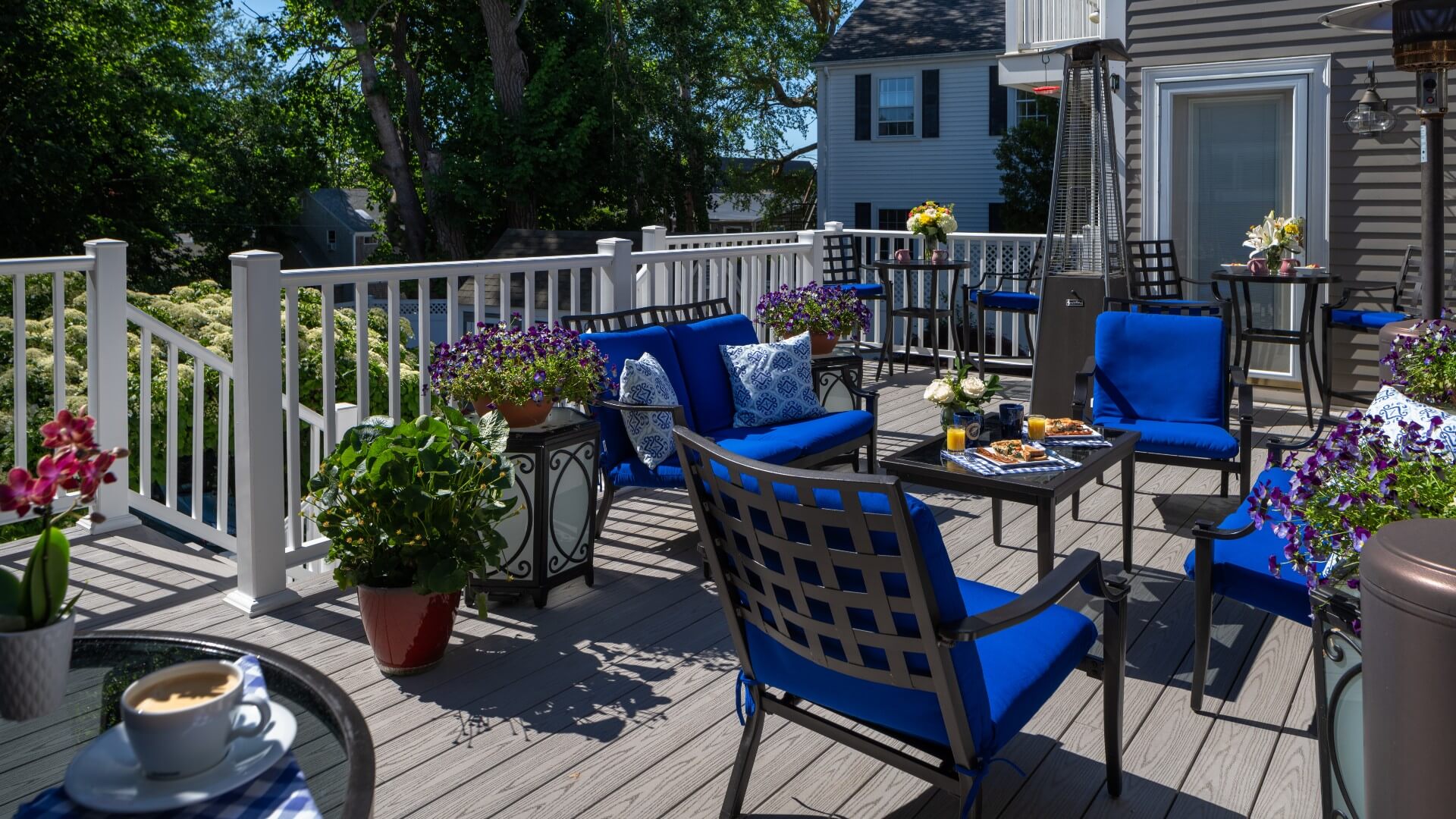 Large outdoor deck with patio chairs and tables and many potted flower plants