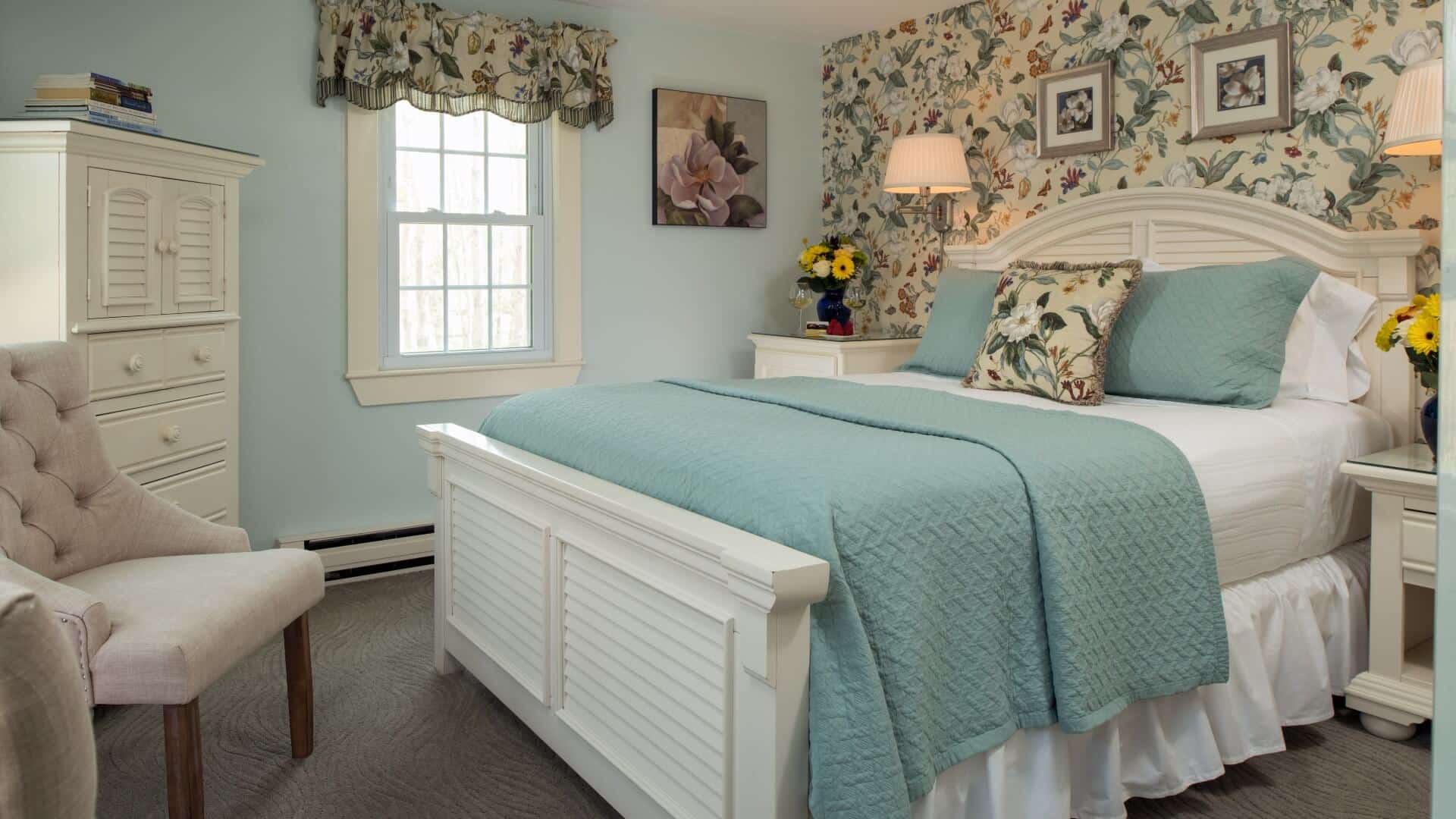 Elegant bedroom with floral wallpaper, queen bed, sitting chairs and window