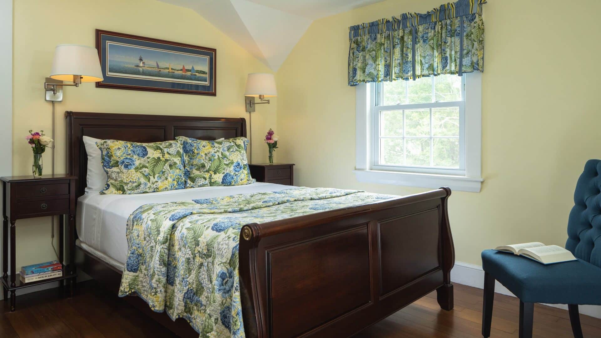 Bedroom with pale yellow walls, bed with floral quilt and bright window