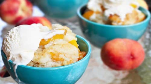 Peach Cobbler in a bowl topped with vanilla ice cream