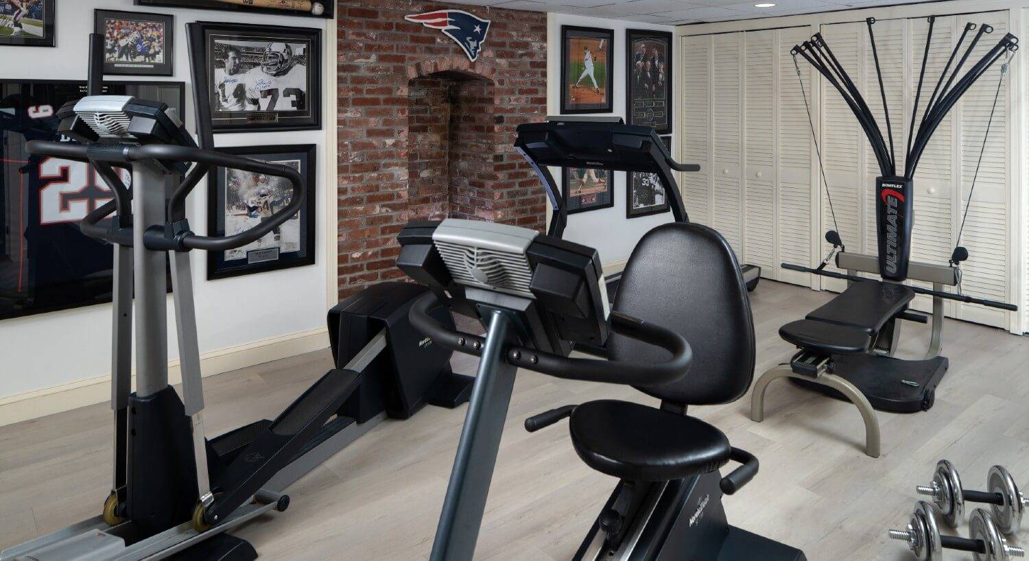 A gym room with various kinds of equipment and sports pictures on the walls