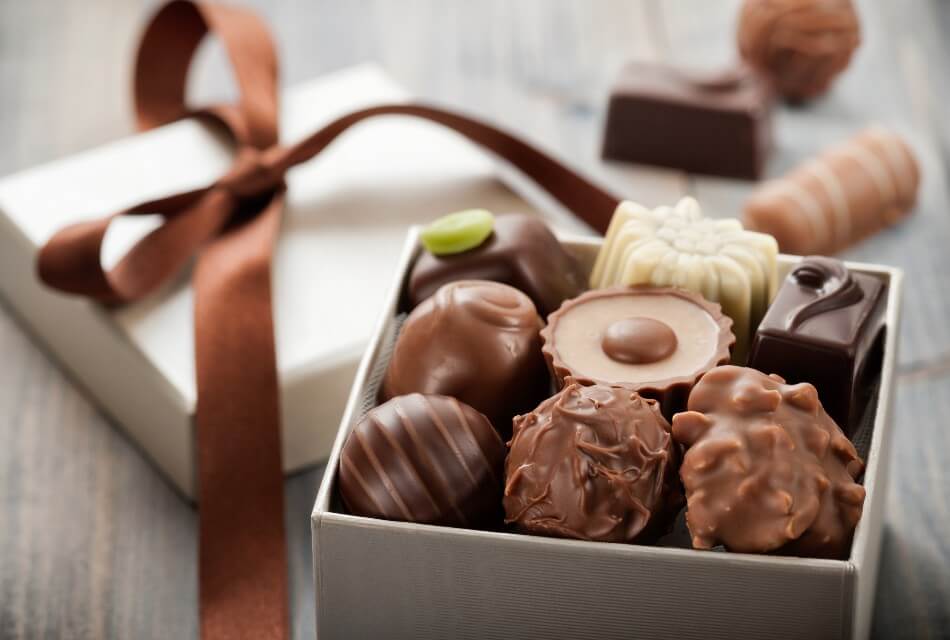 Small white box of assorted chocolates with a brown ribbon