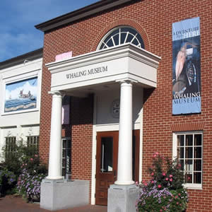 Elegant red brick whaling museum building with white portico and round columns and windows with grids